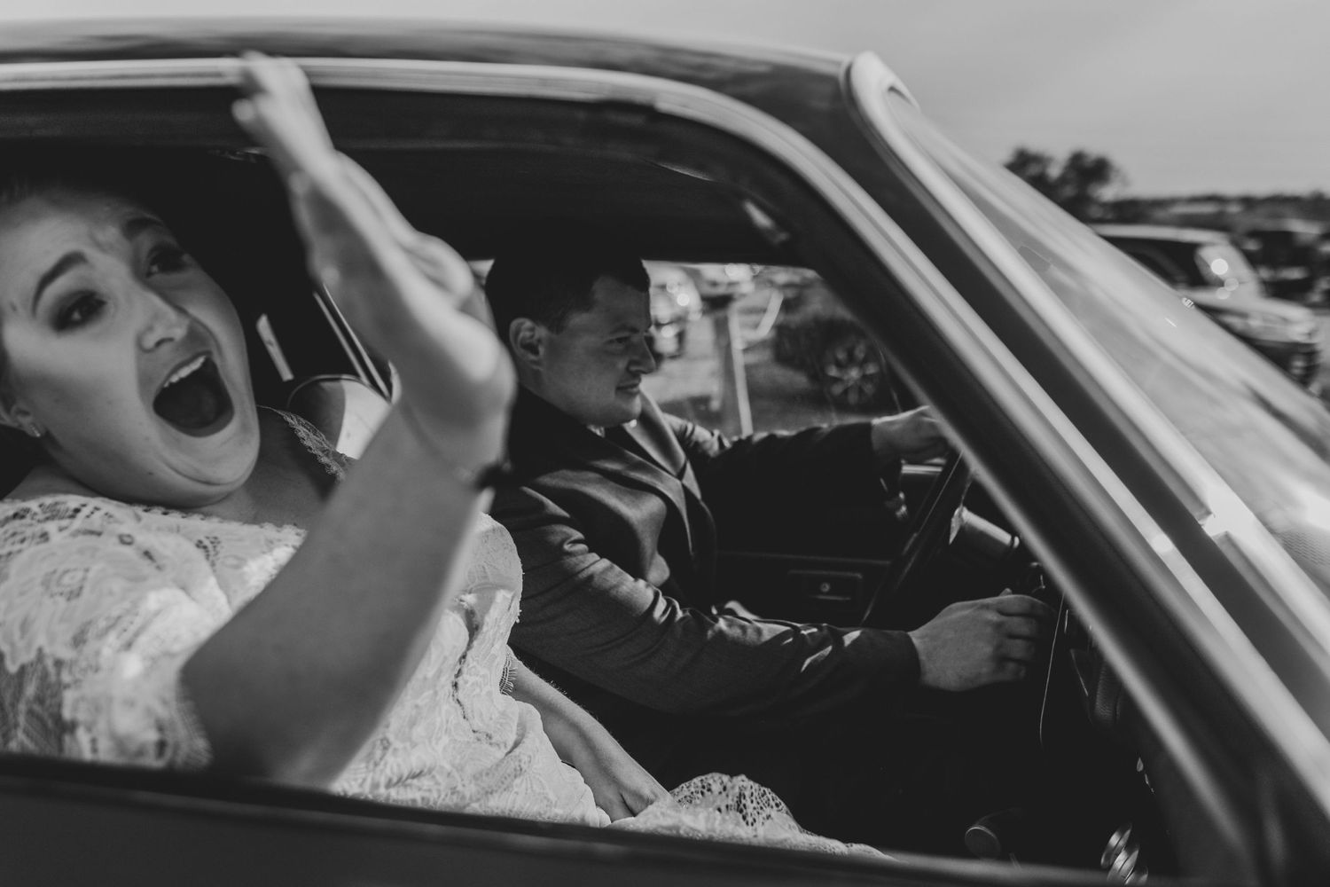 Black and white photo of joyful moment captured inside vintage car.