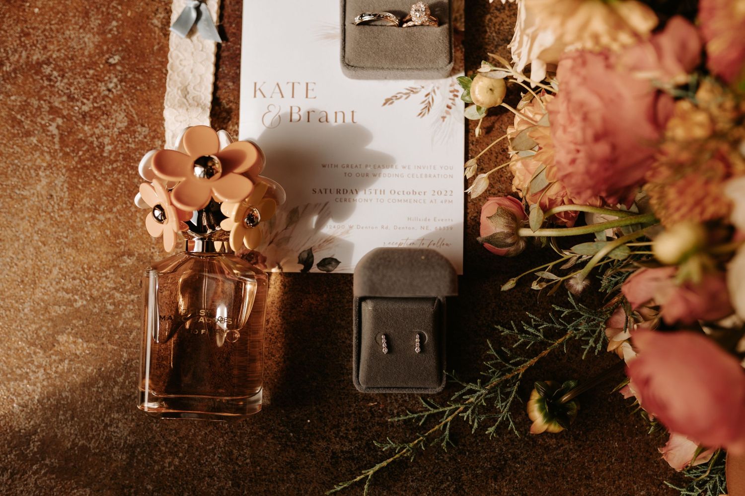 Wedding invitation with ring box and peach flowers in warm lighting.