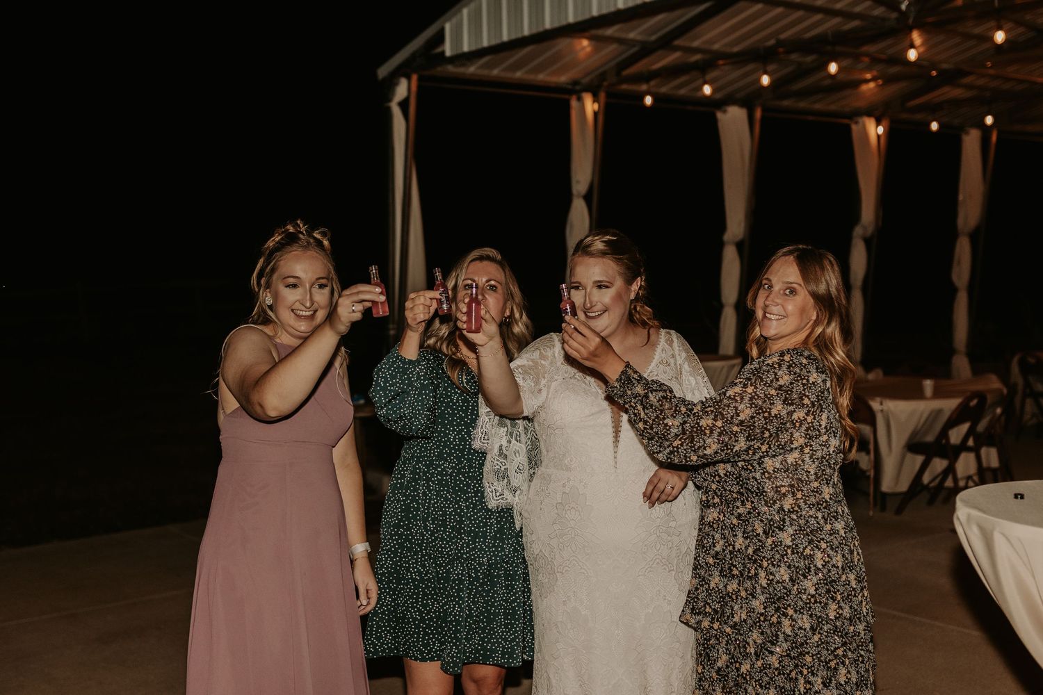 Group celebrates together on an outdoor patio at night during wedding festivities.