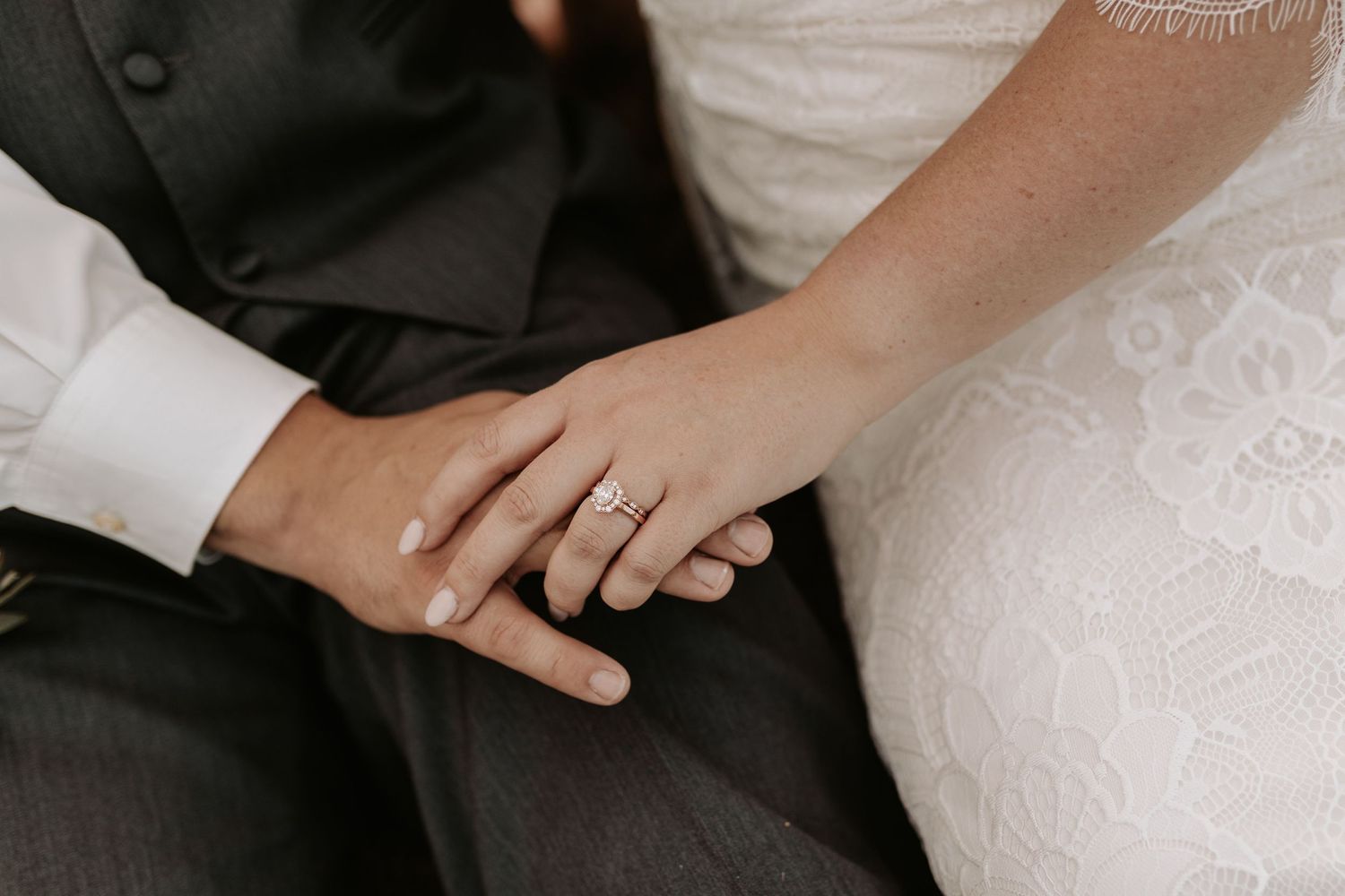 Close-up of wedding rings and lace dress details during an intimate moment.