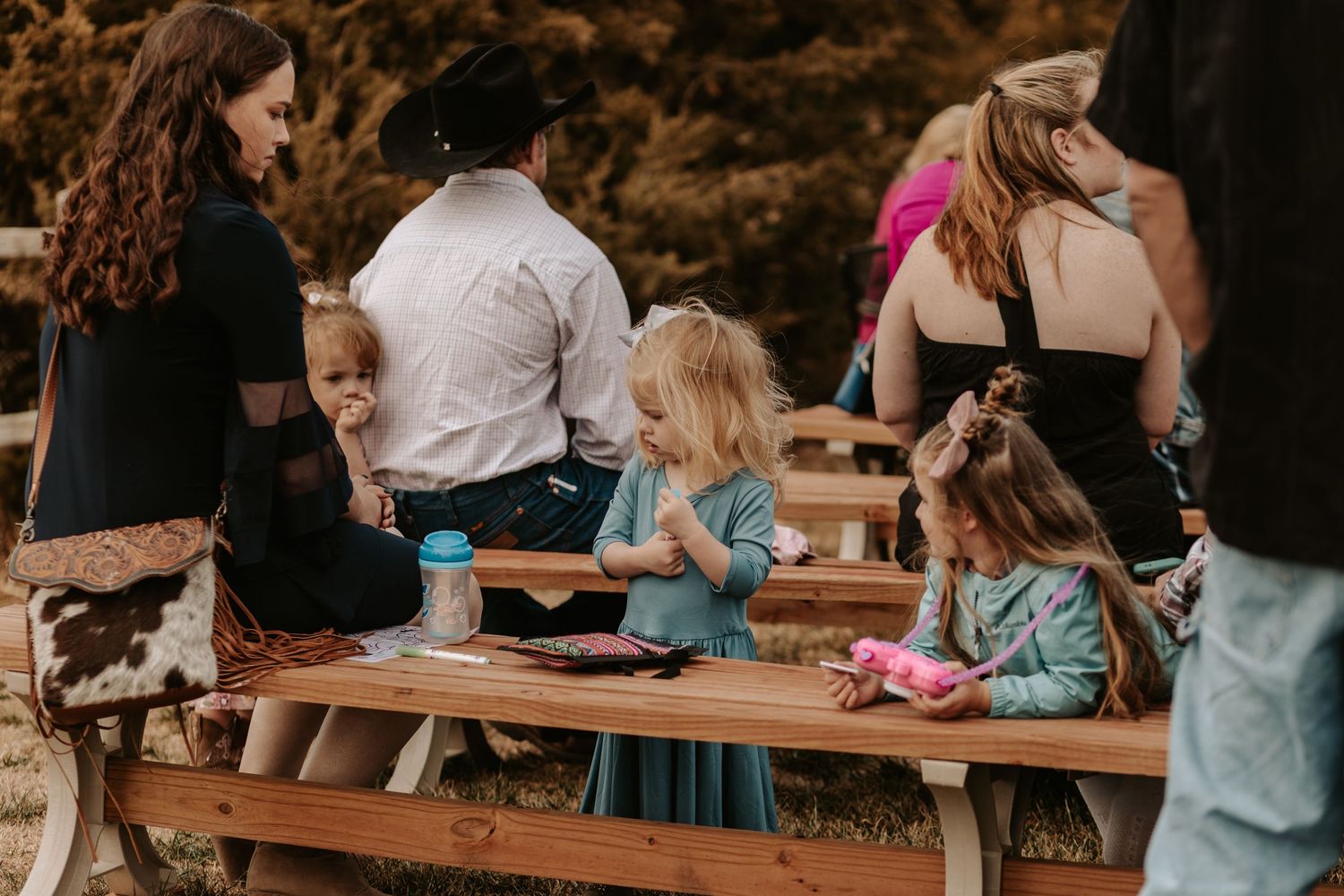 Children and adults gathered at picnic table during outdoor event.