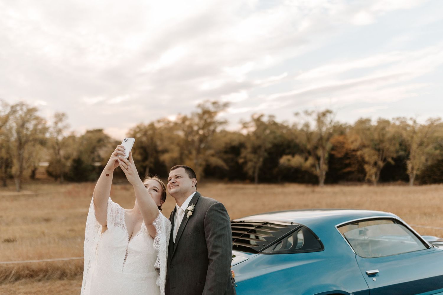 An intimate wedding moment captured against a classic blue car backdrop.