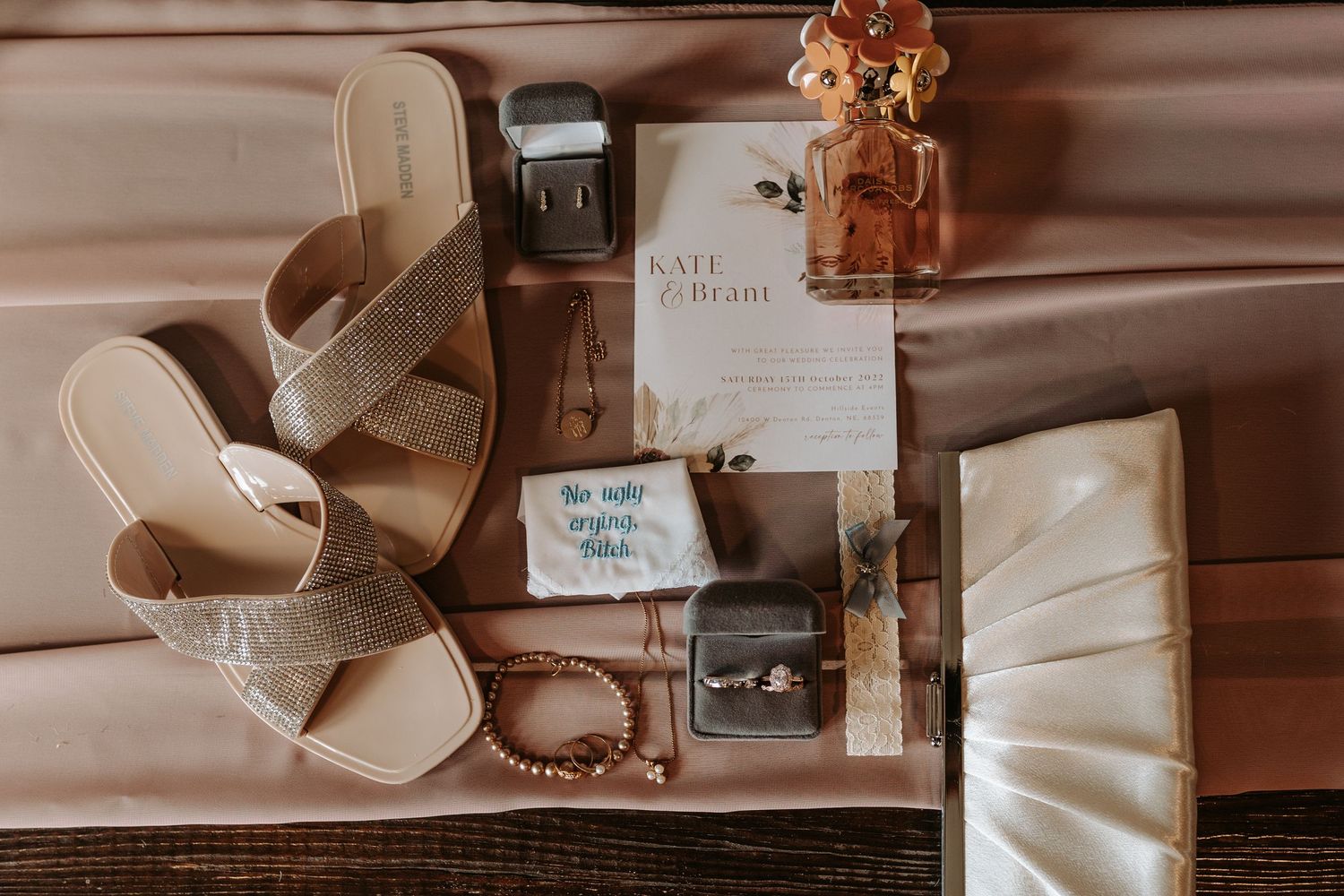 Bridal accessories including beige sandals, perfume, and wedding stationery arranged on surface.
