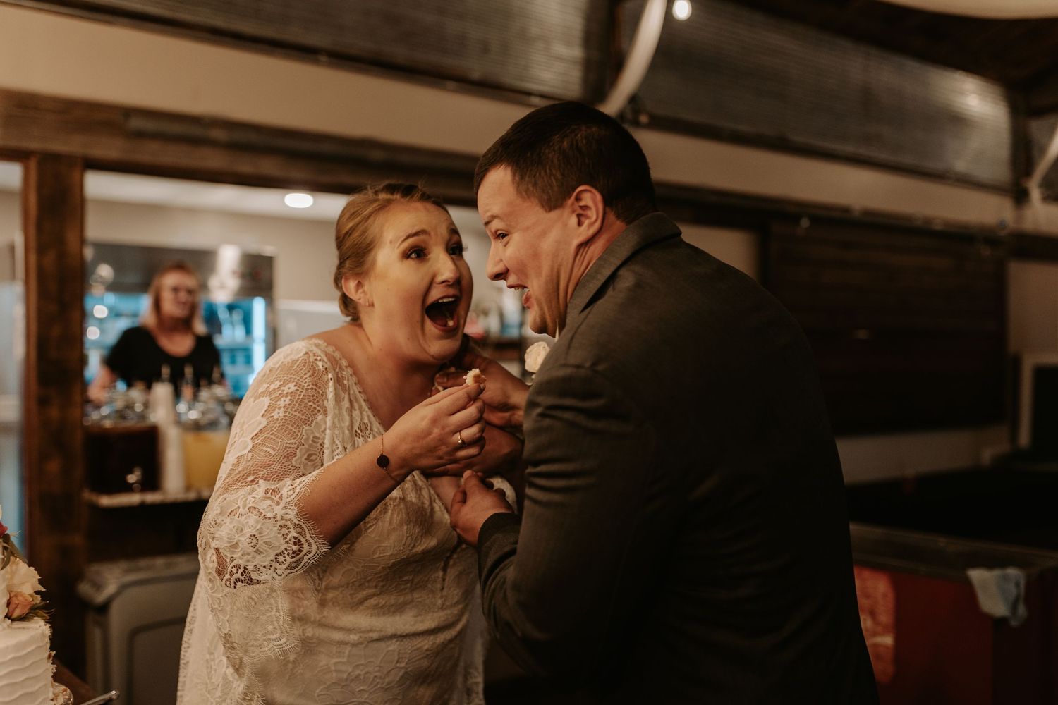 A candid moment of pure joy and laughter during a rustic indoor wedding reception.