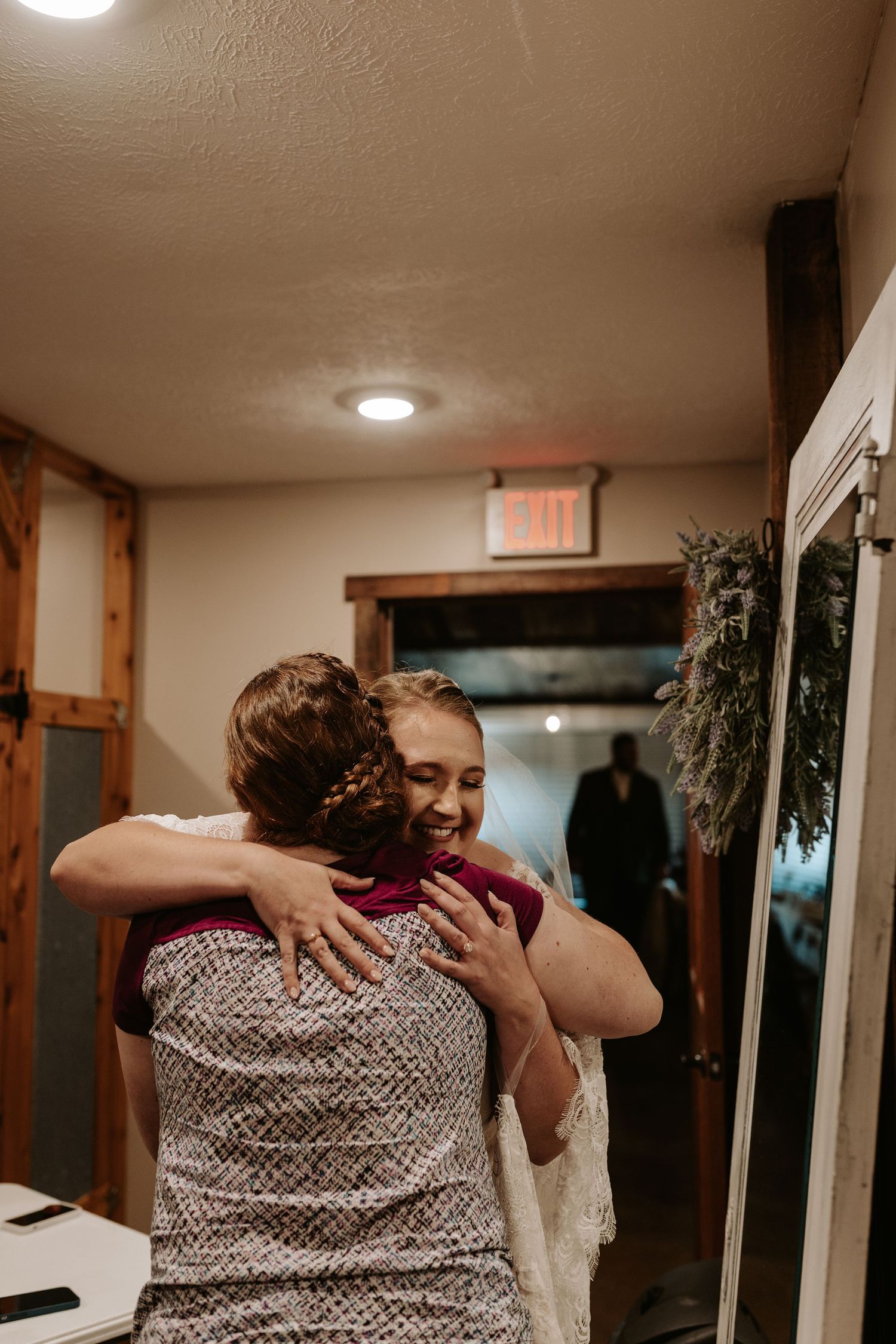 Emotional embrace during wedding celebration in rustic indoor setting.