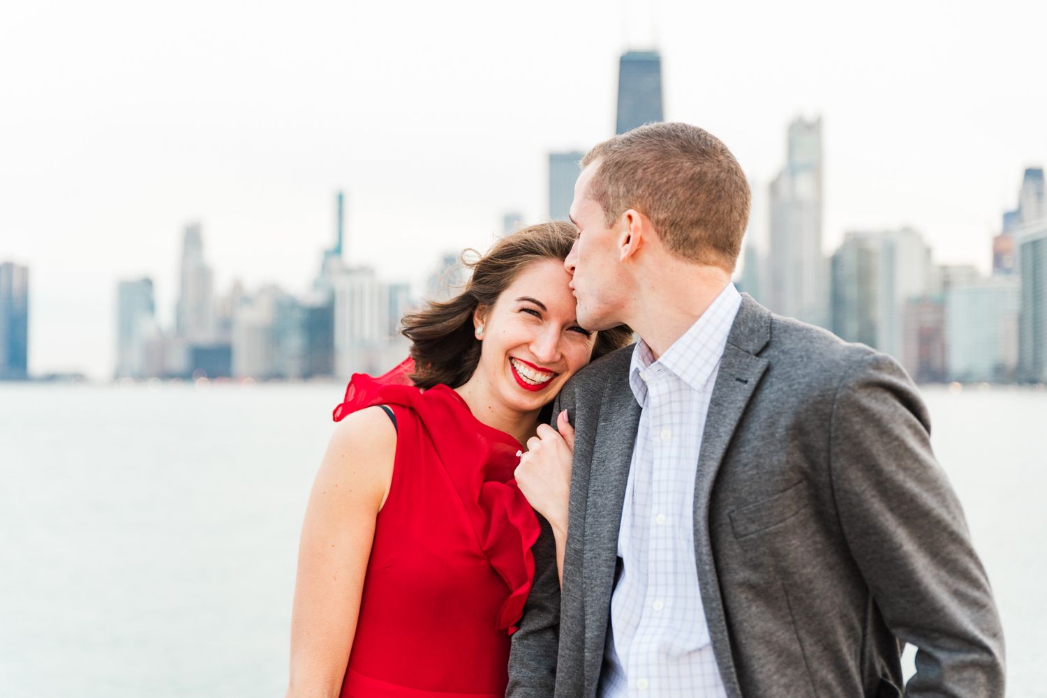 woman leaning on fiance shoulder, both smiling in front of Chicago skyline at North Ave Beach