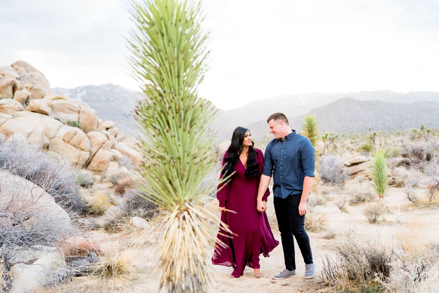 engaged couple holding hands and looking at each other in Joshua Tree park California