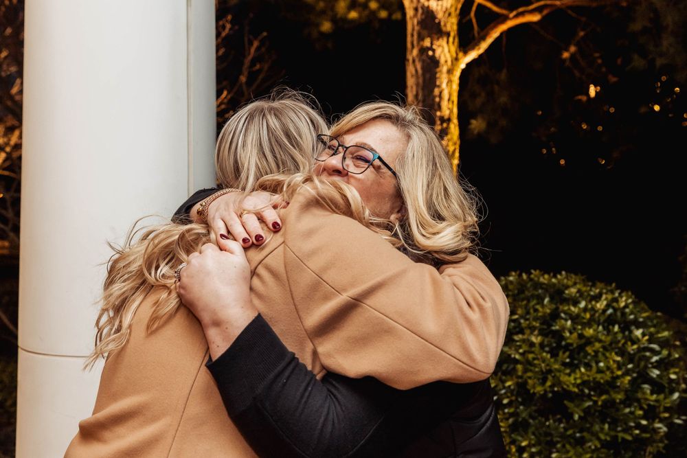 Emotional embrace shared between two people wearing camel and black coats.
