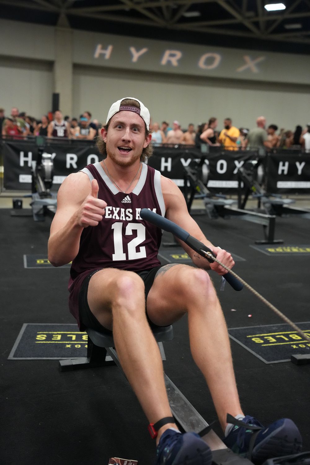 Athlete in Texas jersey exercising on rowing machine during indoor competition.