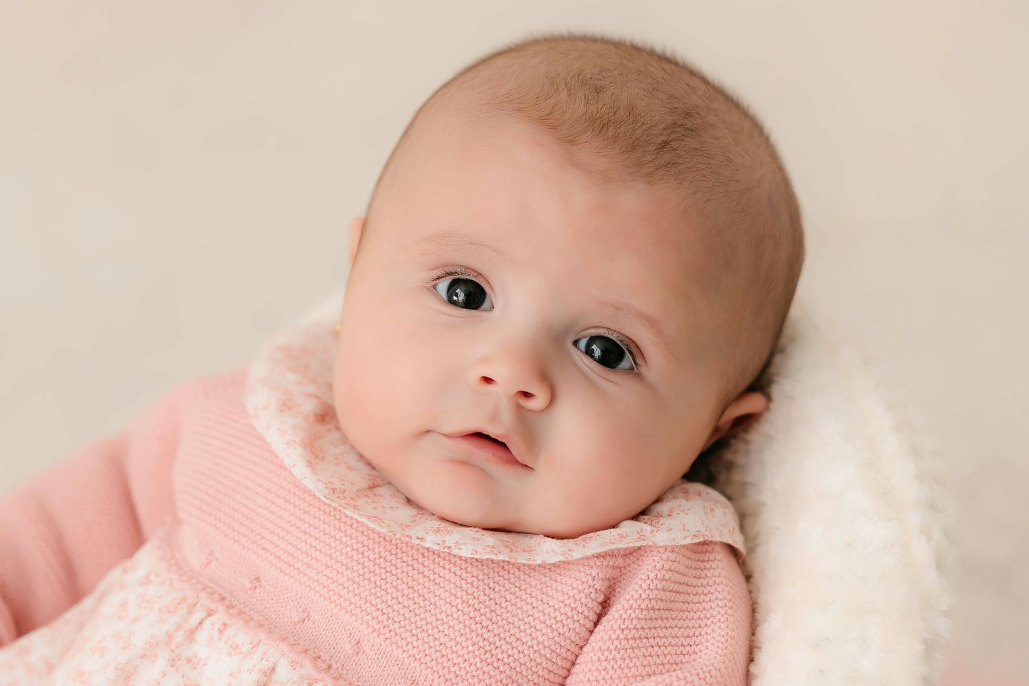 Fotografía de una bebé de tres meses mirando linda en su sesión de seguimiento en estudio.