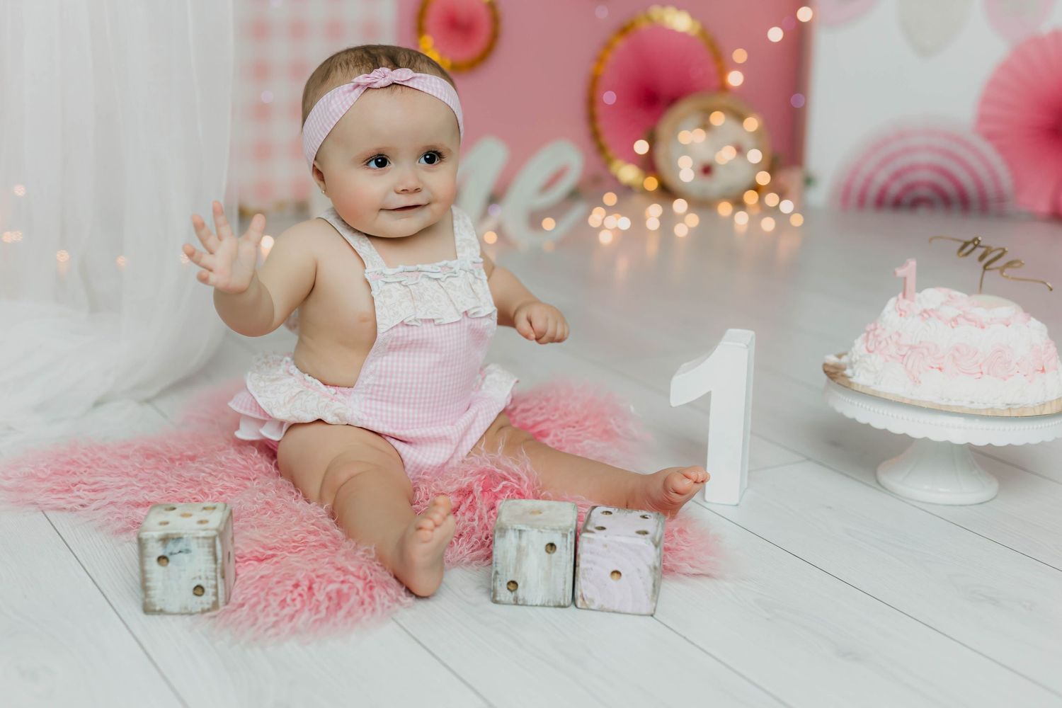 Foto del primer cumpleaños de una niña con tarta y decoración en tonos rosas
