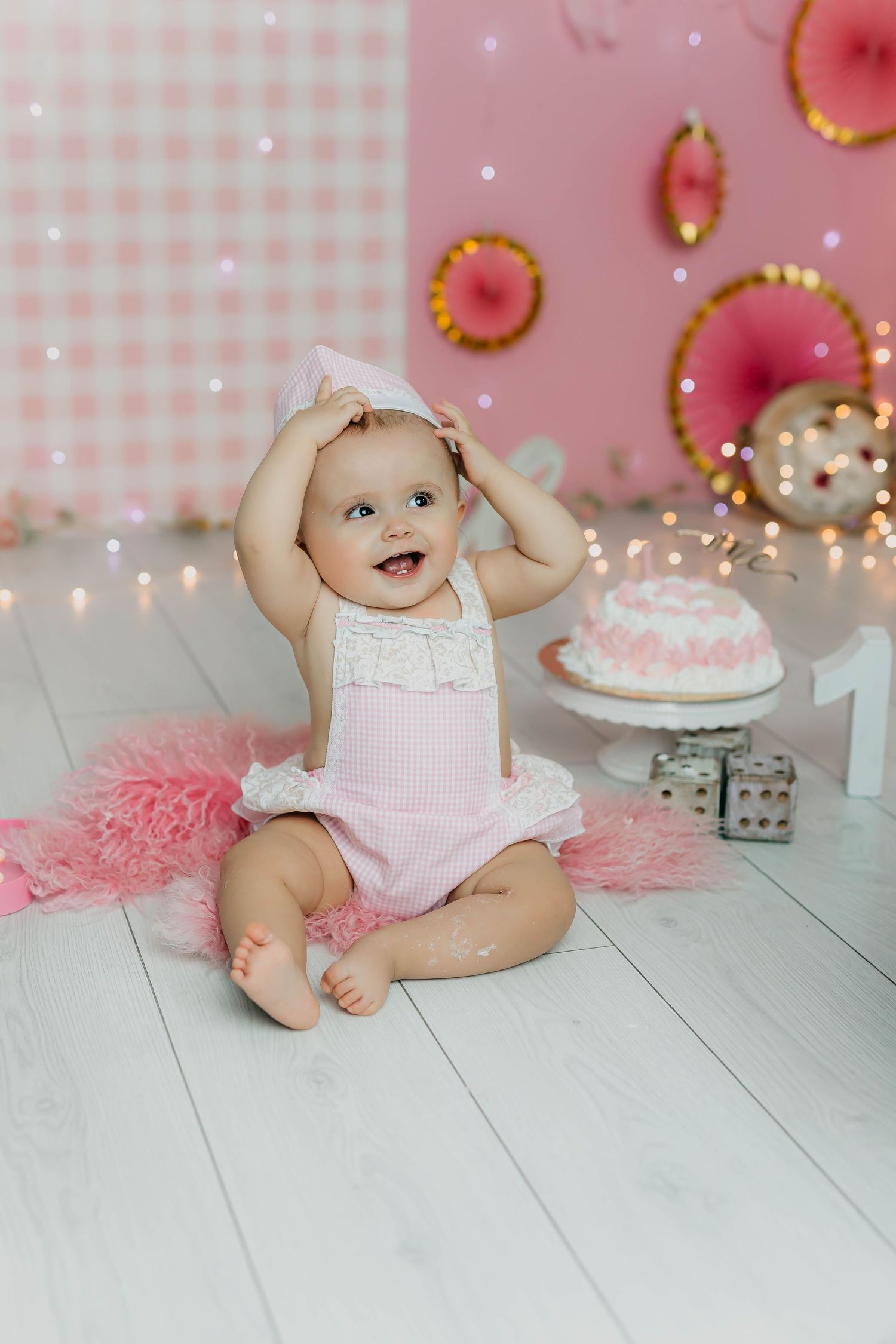 Retrato del primer añito de una niña con tarta y decoración en tonos rosas
