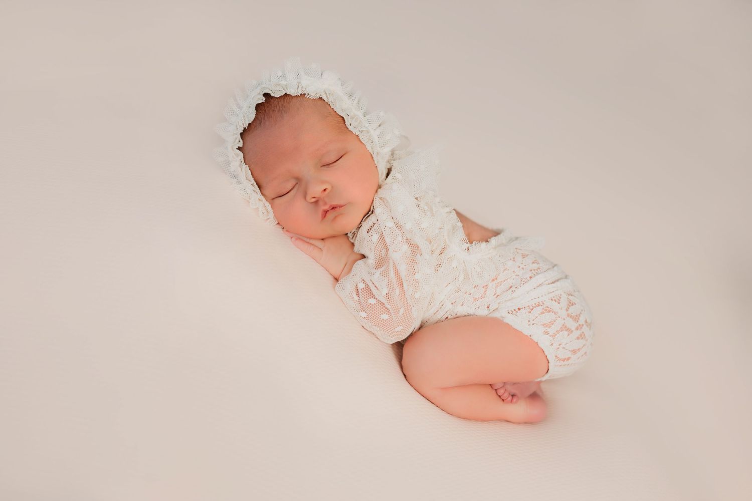 Bebé recién nacida durmiendo en fondo neutro con una linda pose en una sesión fotográfica profesional.
