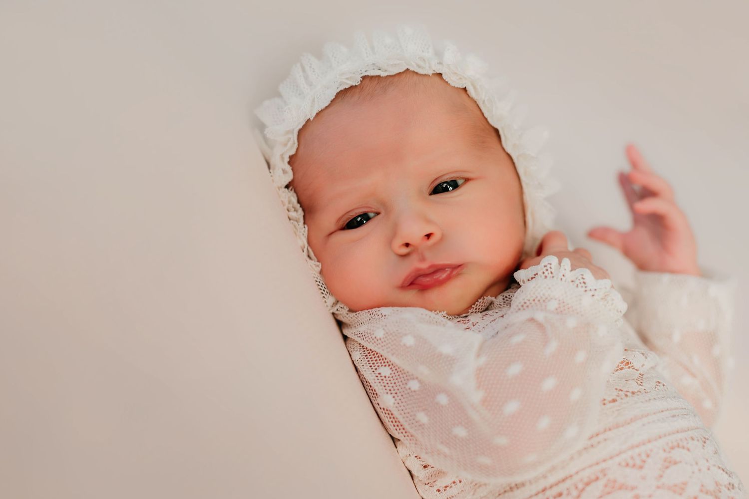 Fotografía de una bebé recién nacida mirando a cámara en una sesión fotográfica profesional.