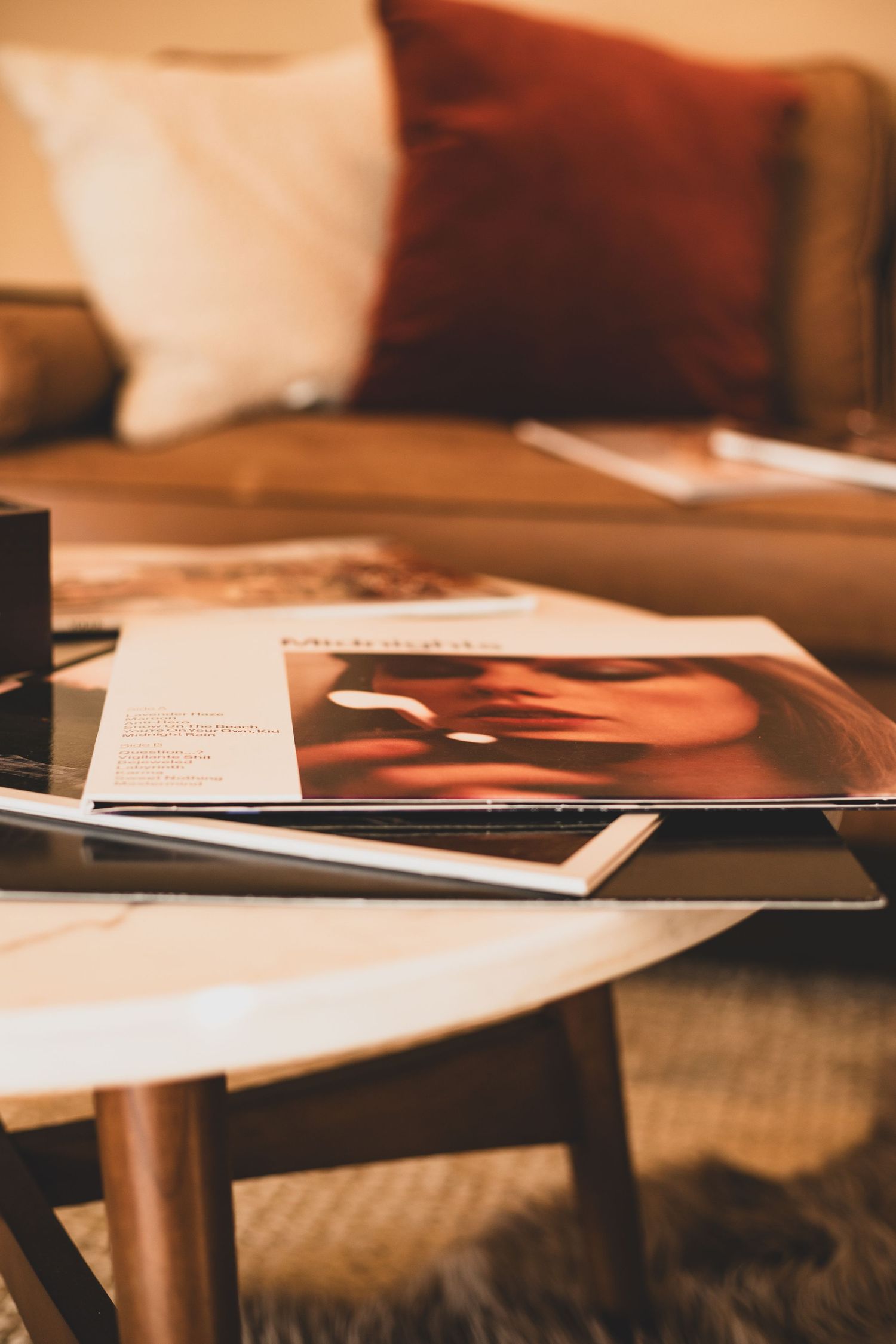 A collection of photographic prints and magazines arranged on a wooden coffee table in warm lighting.