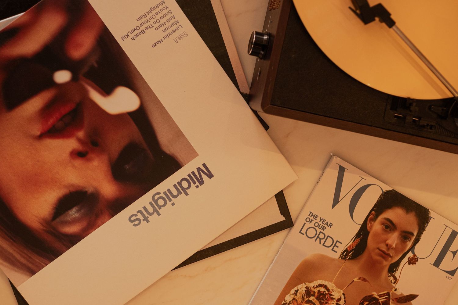 Vintage magazines and vinyl records scattered on a wooden surface in warm lighting.