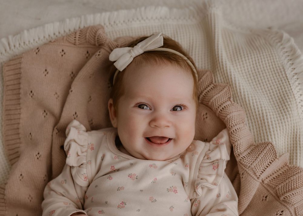 Happy smile with bow headband against cream knitted textures and soft lighting.