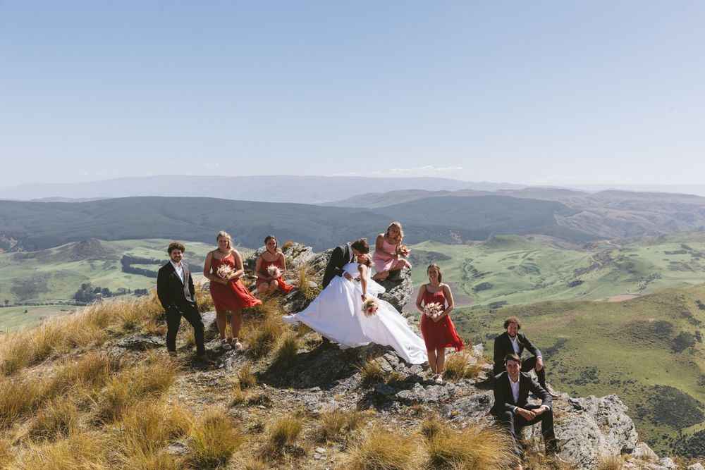Wedding celebration on mountain summit with panoramic views of rolling hills and valleys.