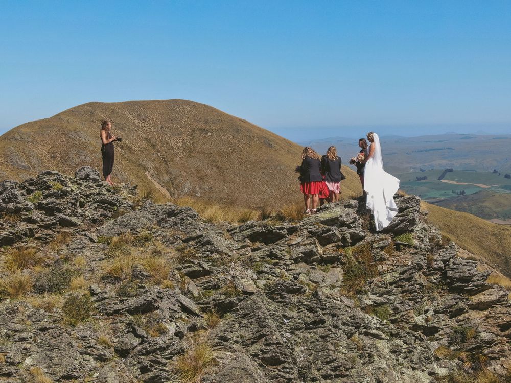 Small wedding gathering on rocky mountain peak with distant valley views.