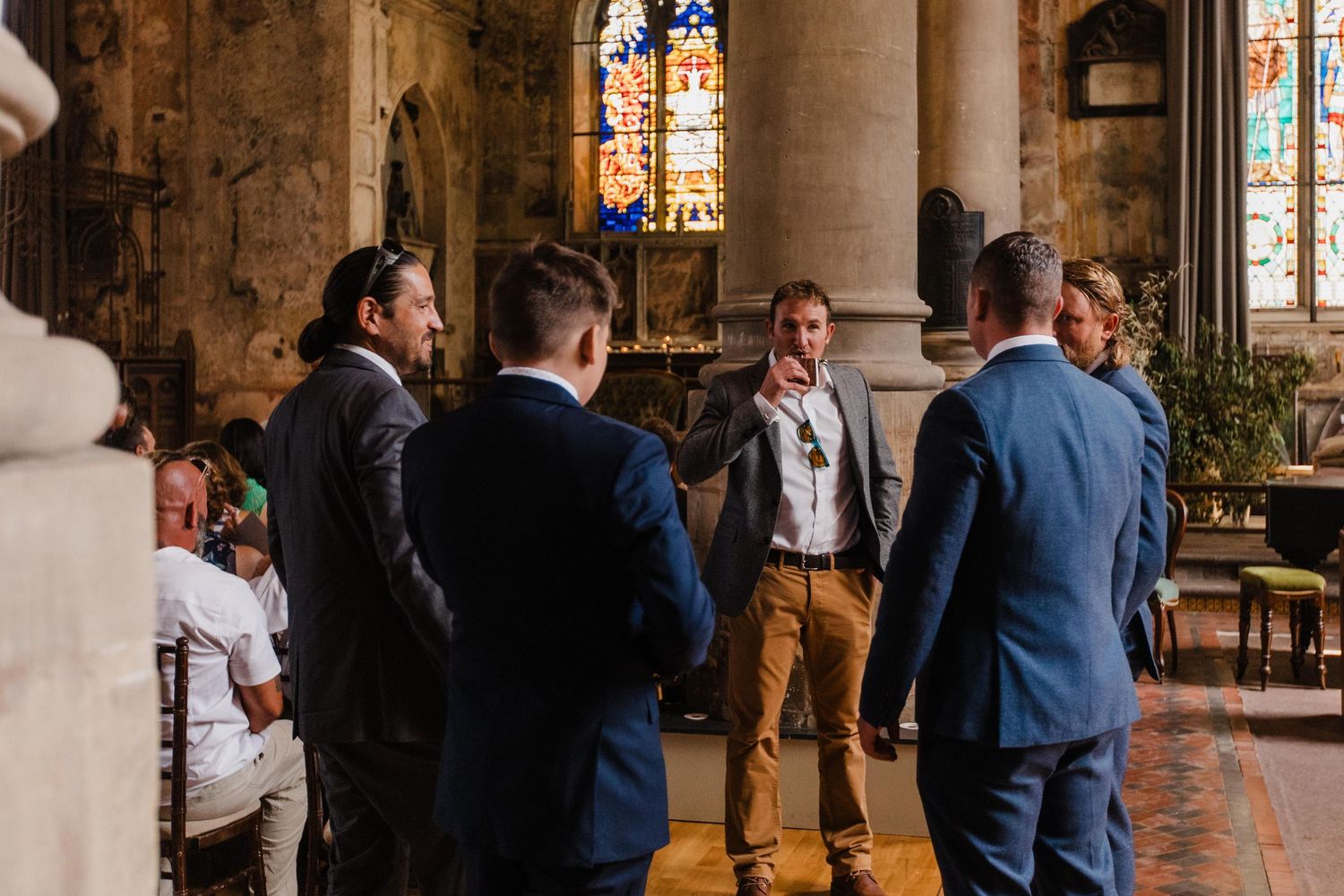 Group gathered inside historic church with stained glass windows and stone architecture.