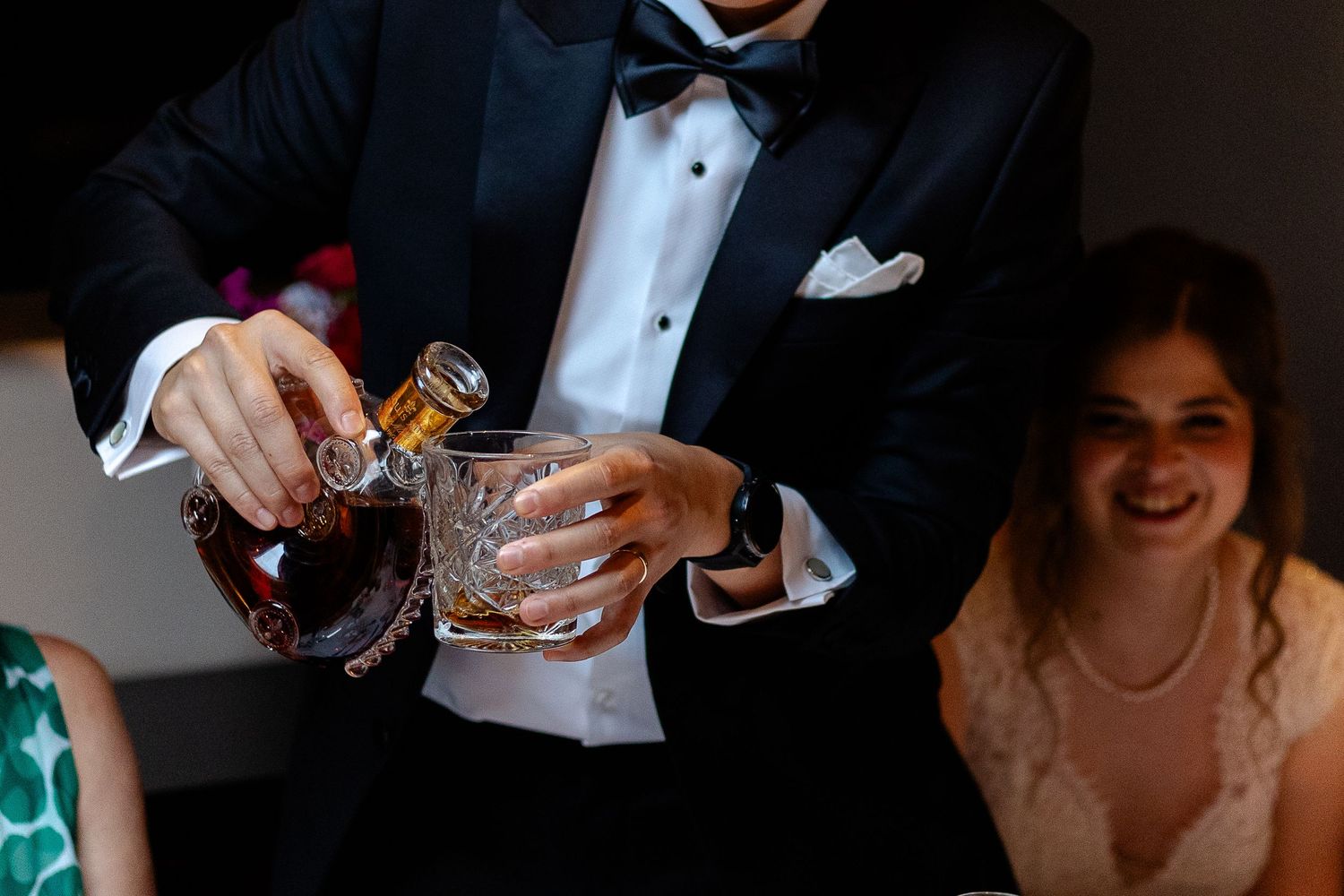 Person in formal attire pouring a cocktail at an elegant event.