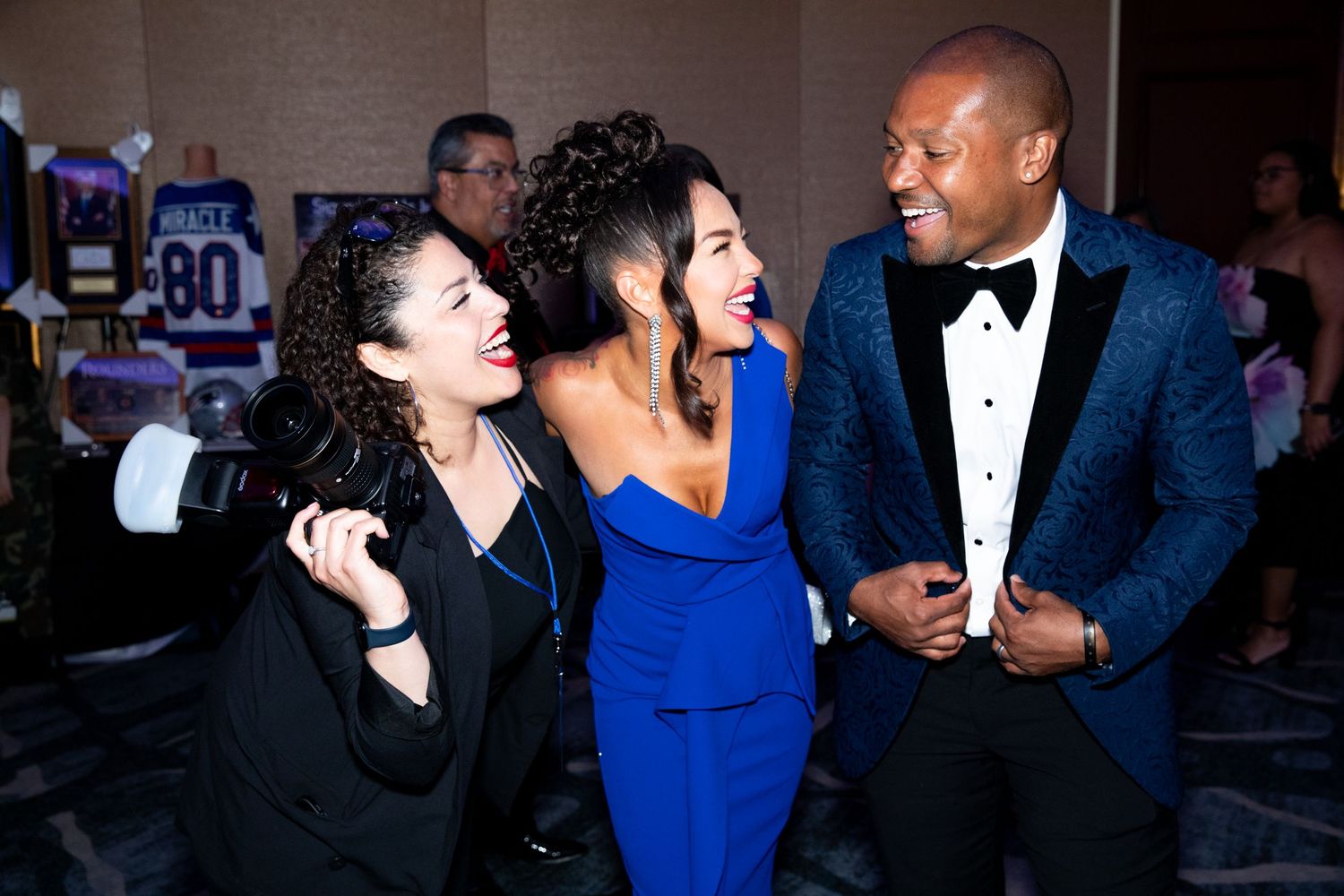 Elegant evening event with guests in formal attire laughing and socializing.
