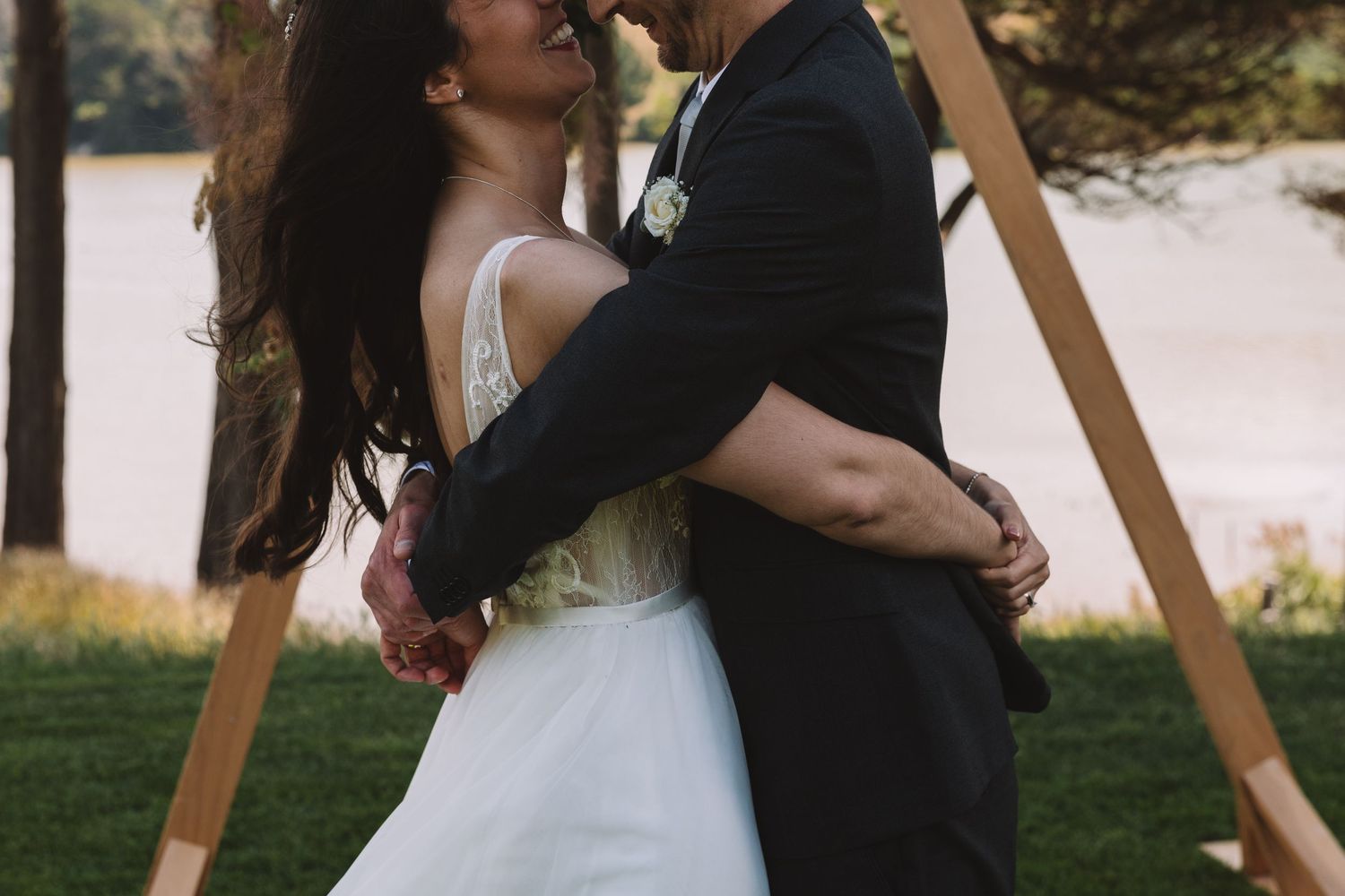 A tender wedding embrace captured outdoors with wooden arches in the background.