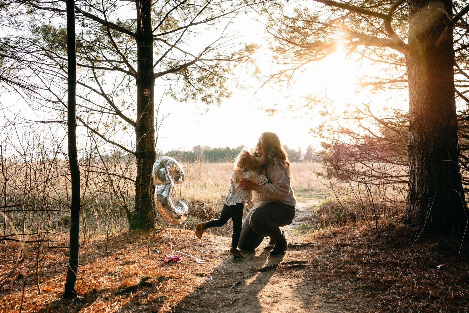 Golden sunlight filtering through trees on a nature path during sunset.