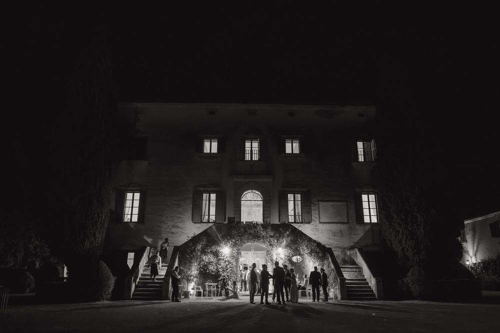 A long dark corridor with illuminated windows and archways in a historic European building at night.