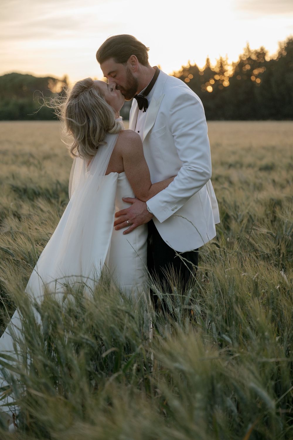 Romantic wedding couple embraces in golden wheat field at sunset photographed in multiple artistic poses.
