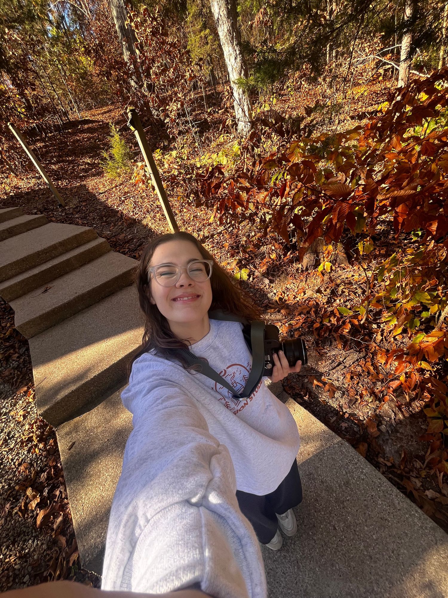 A selfie on an outdoor hiking path surrounded by autumn foliage and trees during fall season.