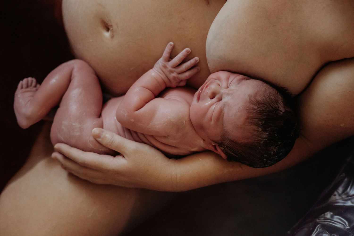 Newborn baby resting skin to skin with gentle support.