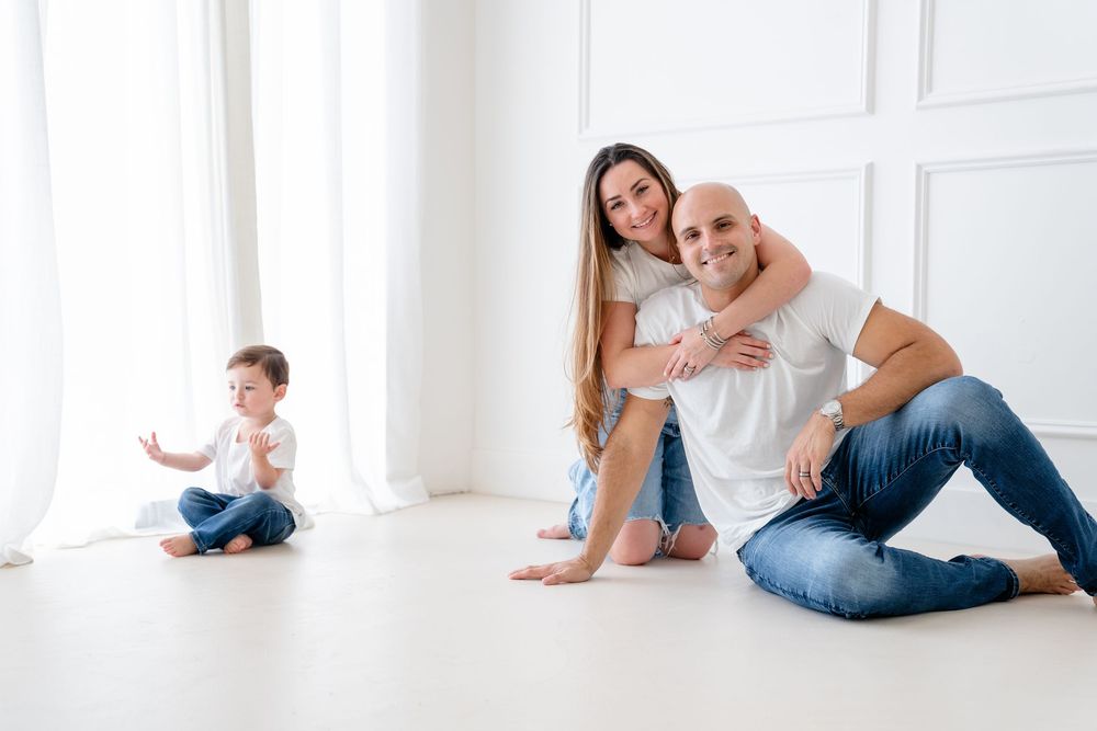 Family spending quality time together sitting and playing in bright white minimalist room.