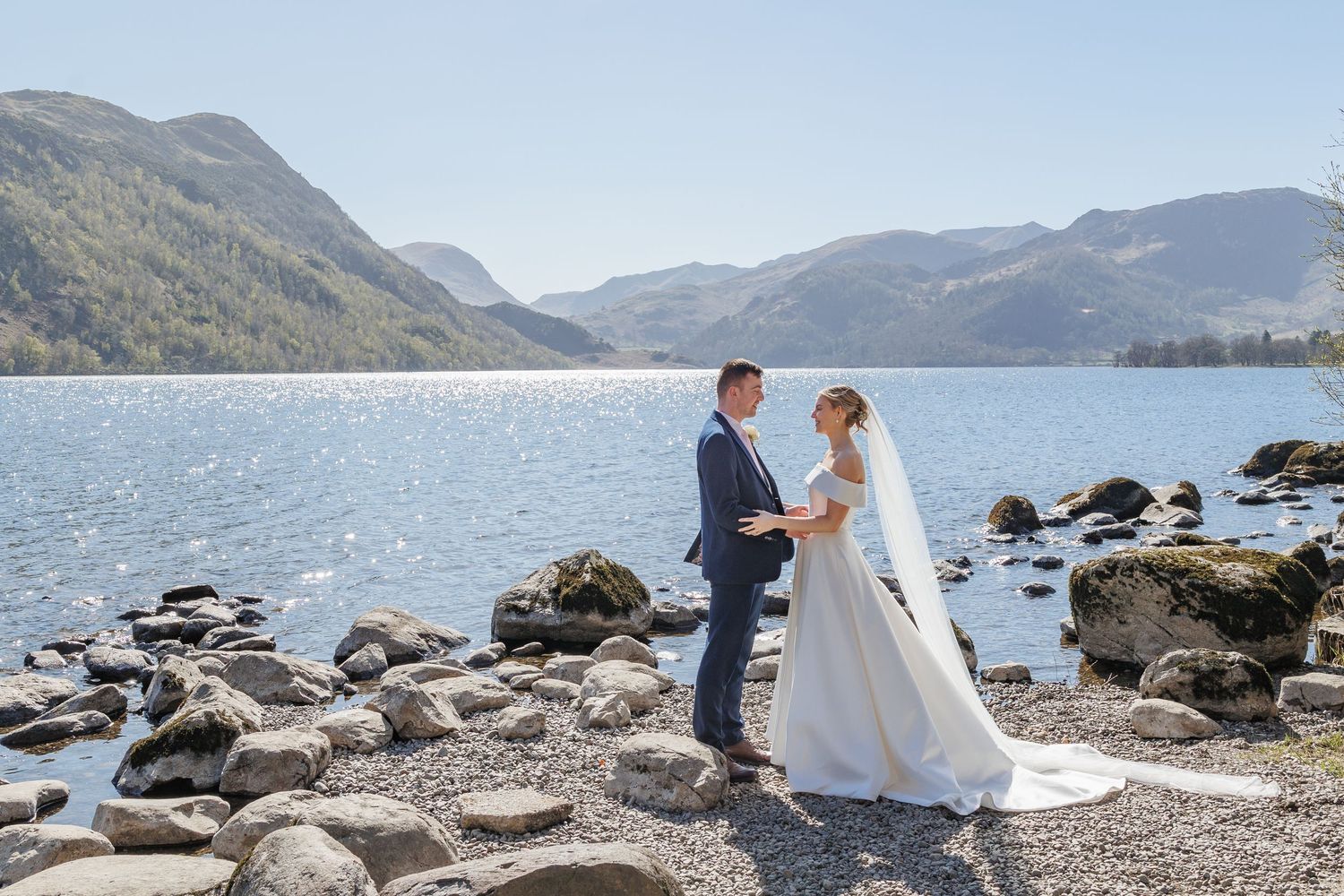 Wedding ceremony by scenic mountain lake with rocky shoreline.