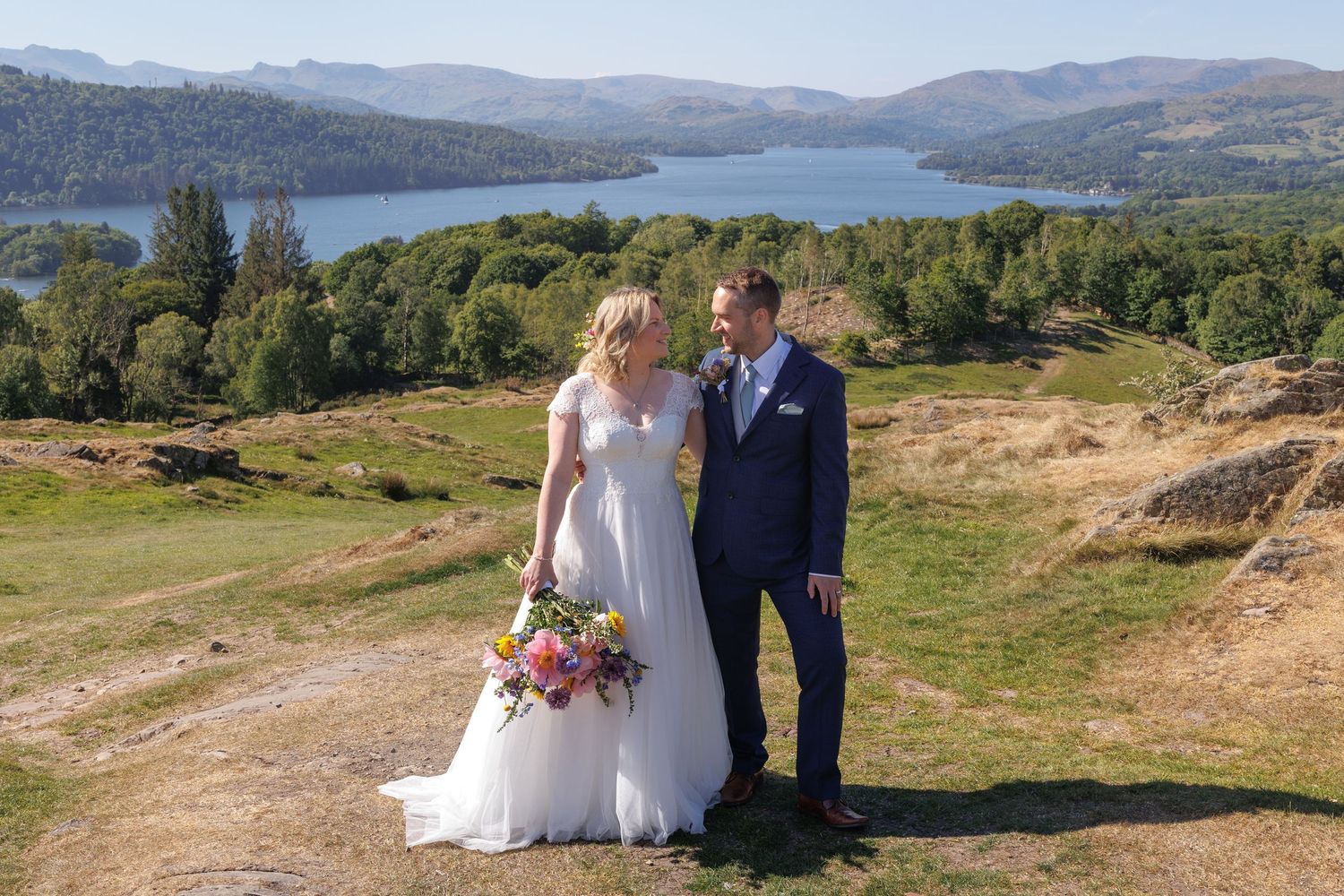 Wedding portrait overlooking scenic lake and mountain vista.