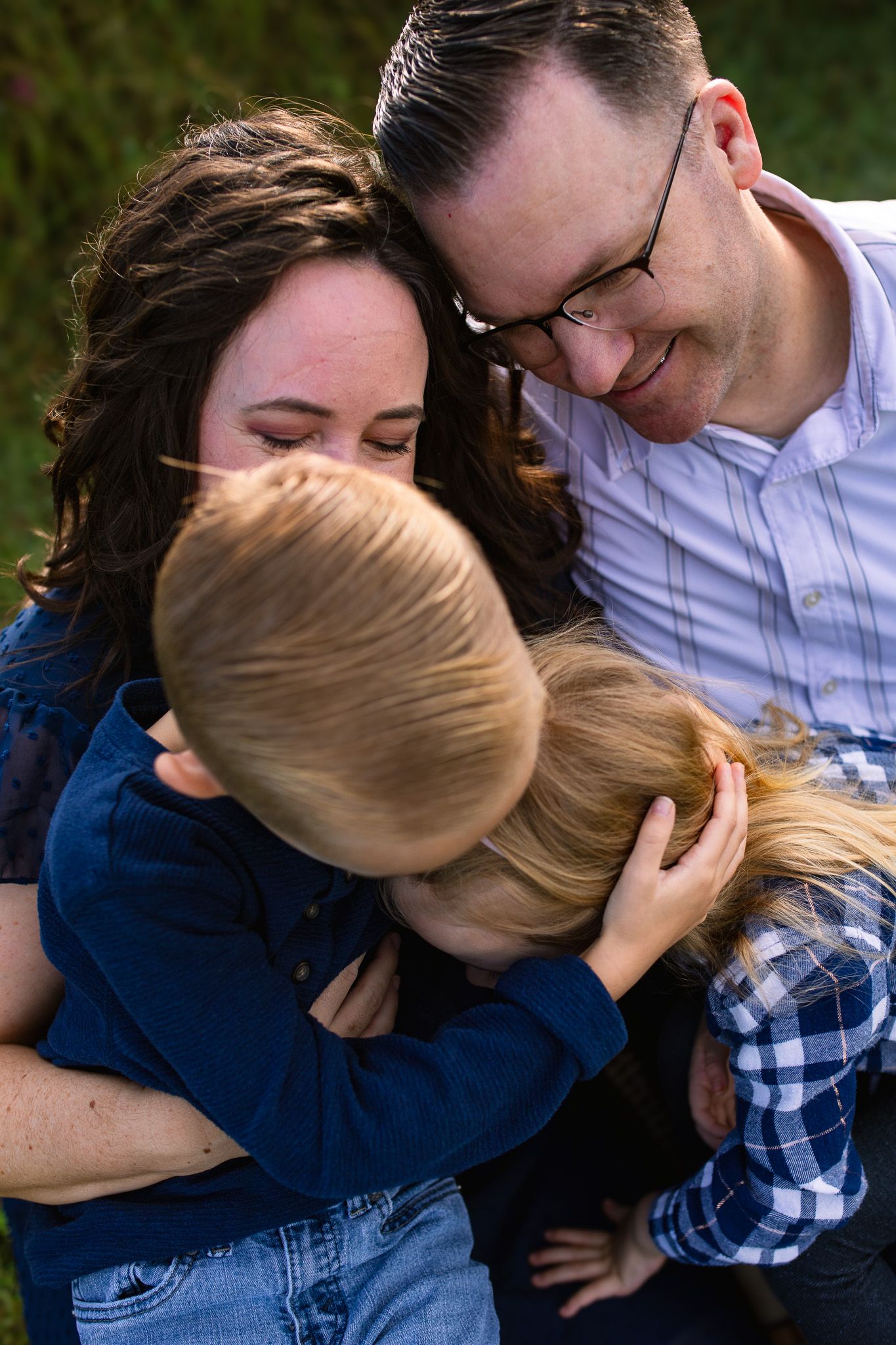 Intimate family moment outdoors showing parents embracing their child with genuine affection and smiles at Juniper Creek Farm