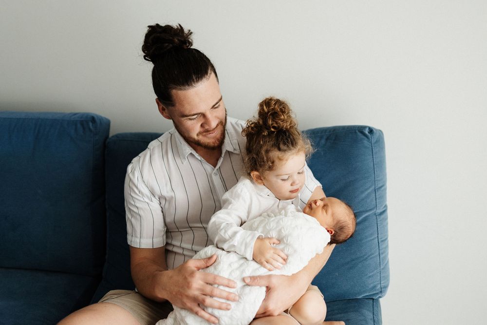 A tender family moment on a blue couch with a newborn baby.