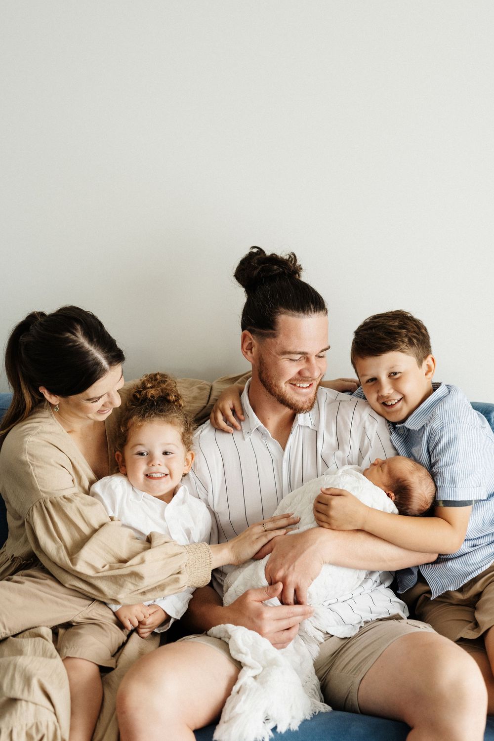 Family bonding moment showing affection and cuddles on a cozy white couch.
