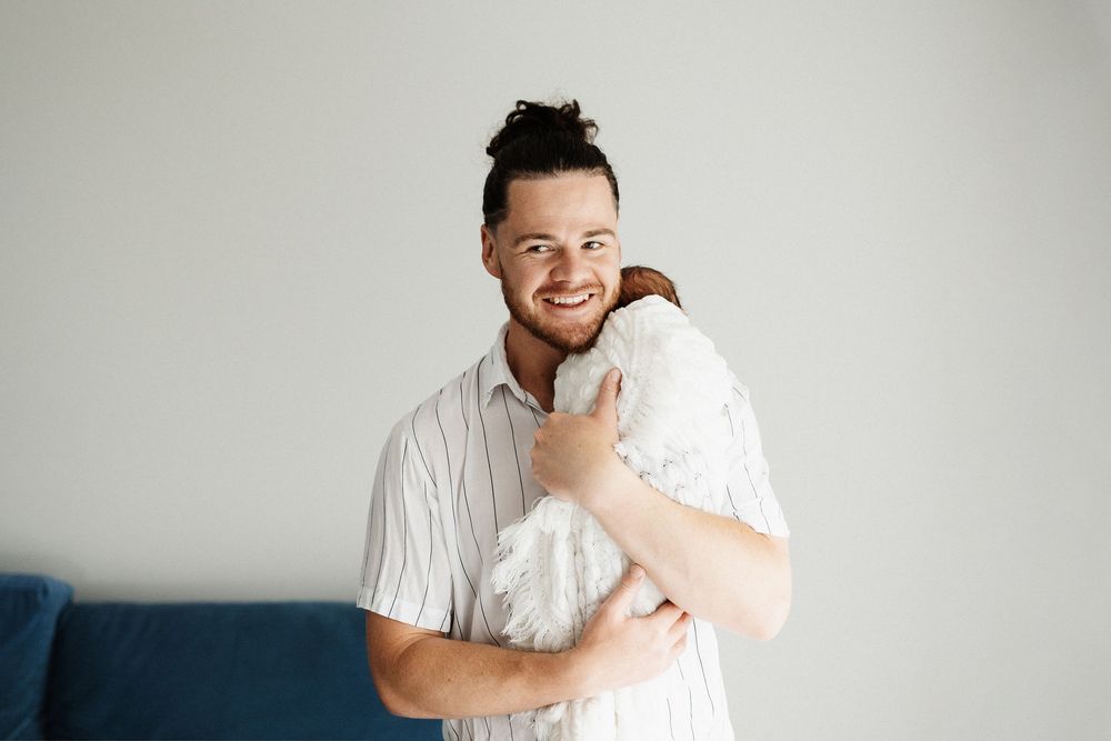 Intimate family portrait against white background showing tender interactions with a newborn.