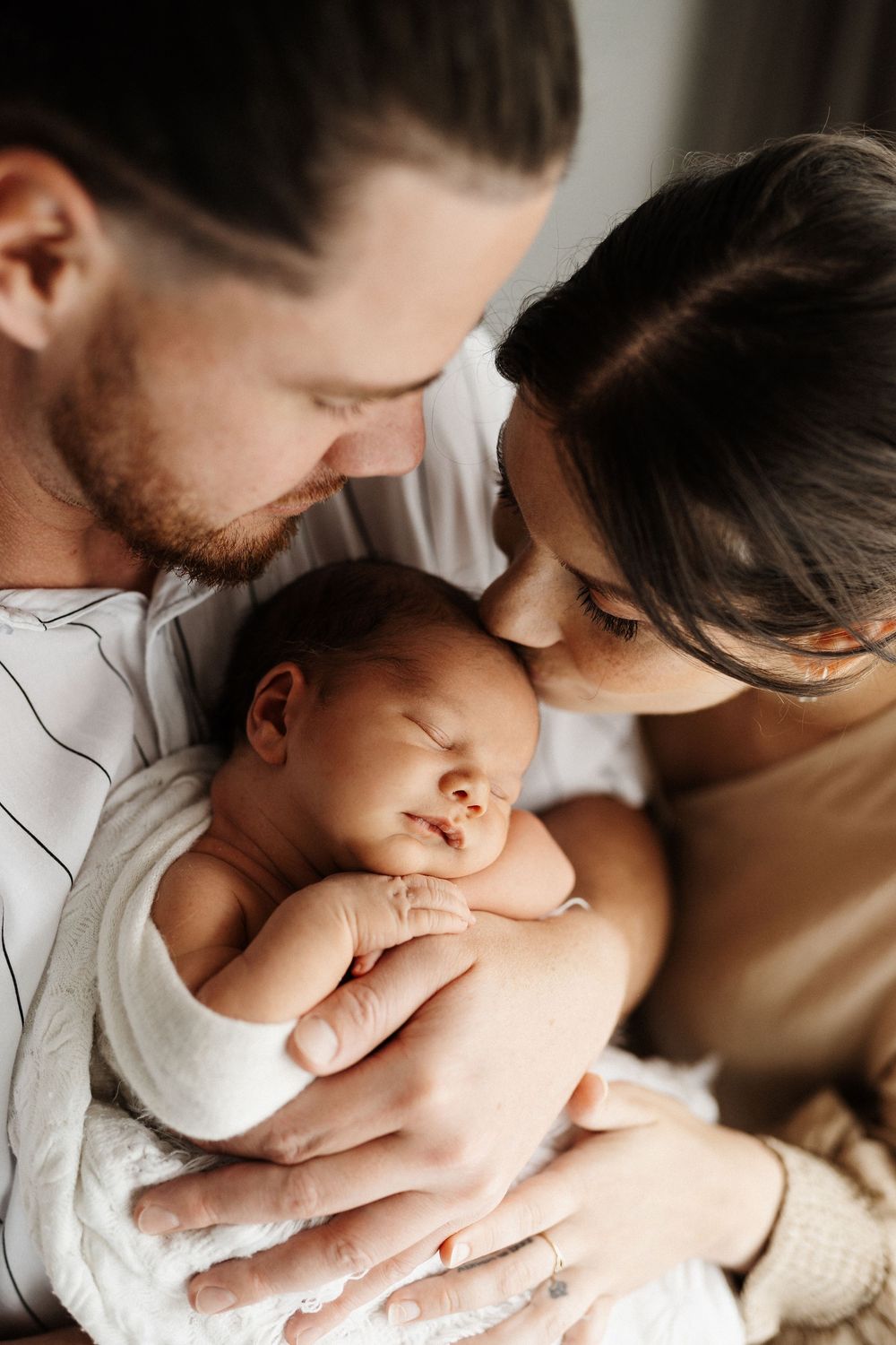Close-up intimate moment of family members snuggling with a newborn baby.