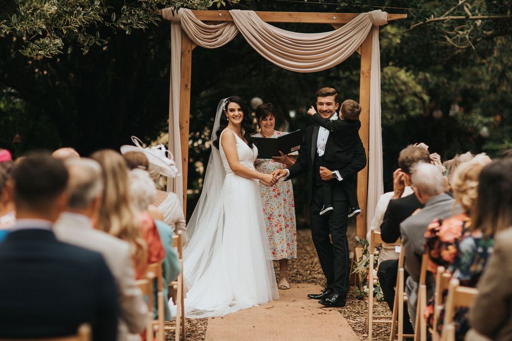 Romantic outdoor wedding ceremony under elegant white draped fabric decor at a scenic venue at Hirst Priory.