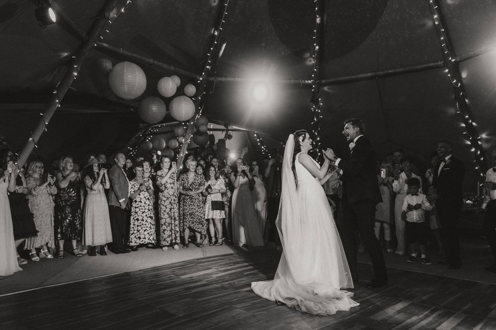 Newlyweds perform their first dance surrounded by guests with sparklers creating a magical glow on the dance floor at Hirst Priory.