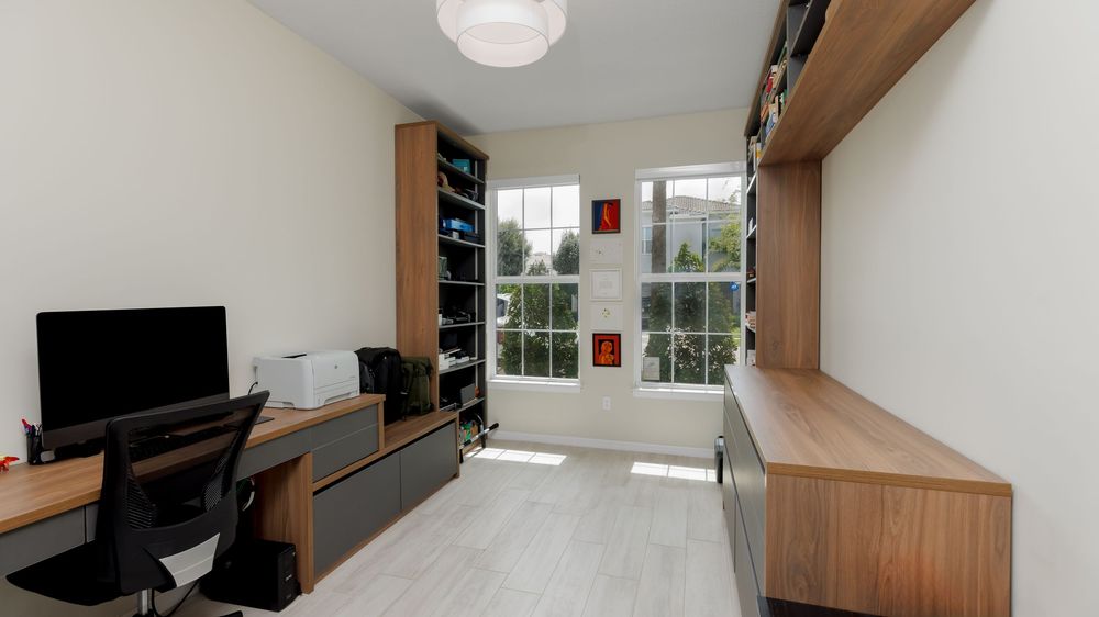 Contemporary home office with built-in wood cabinetry, large windows providing natural light, and minimalist décor featuring a modern desk a