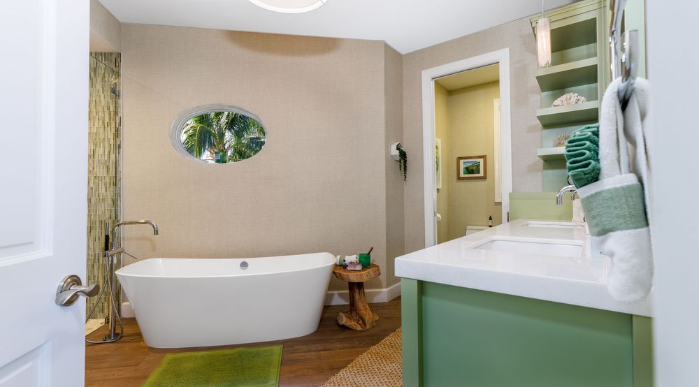 Modern bathroom with freestanding tub, green vanity, and wood floors.