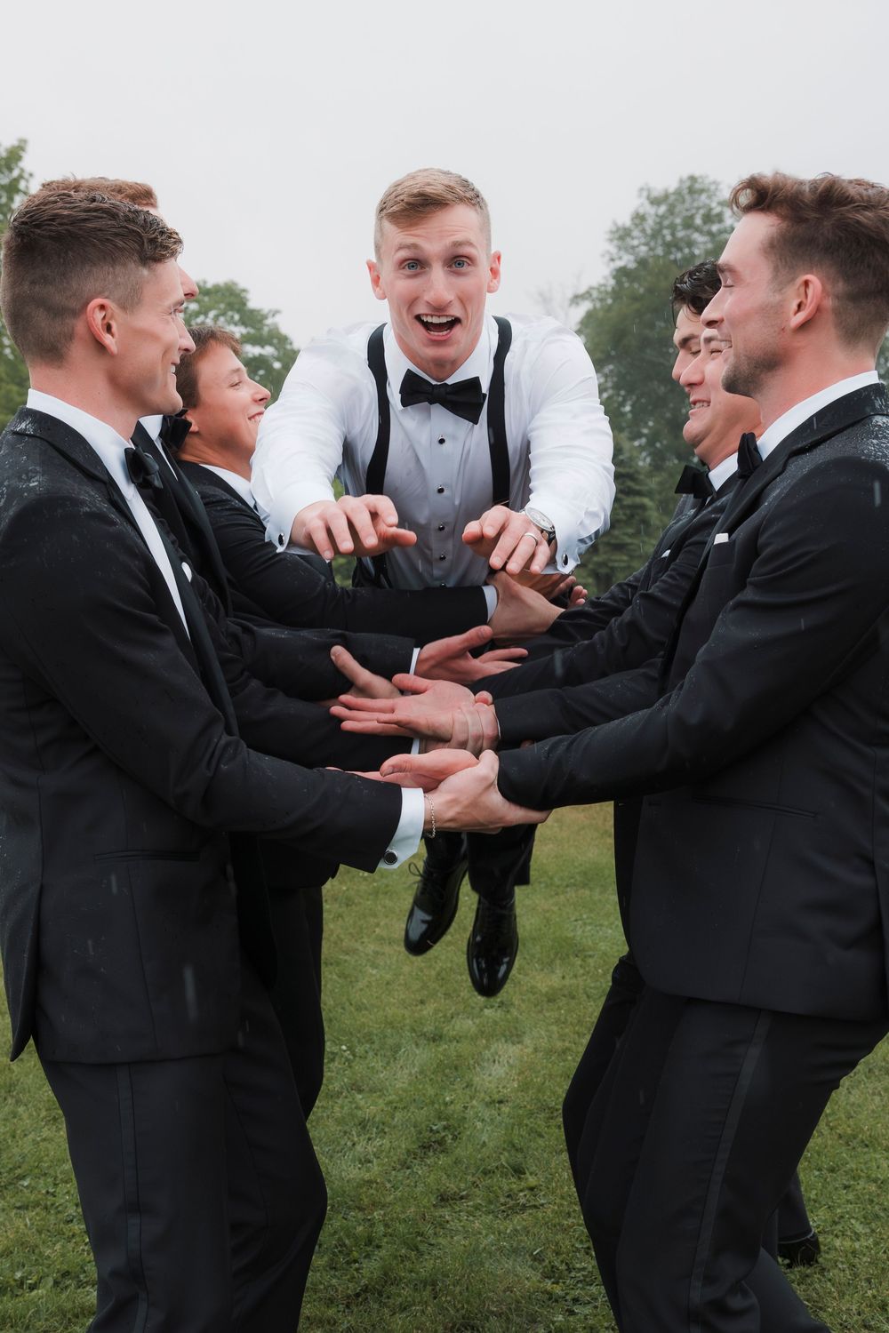 A sequence of photos showing groomsmen in black tuxedos playfully interacting outdoors on grassy grounds.