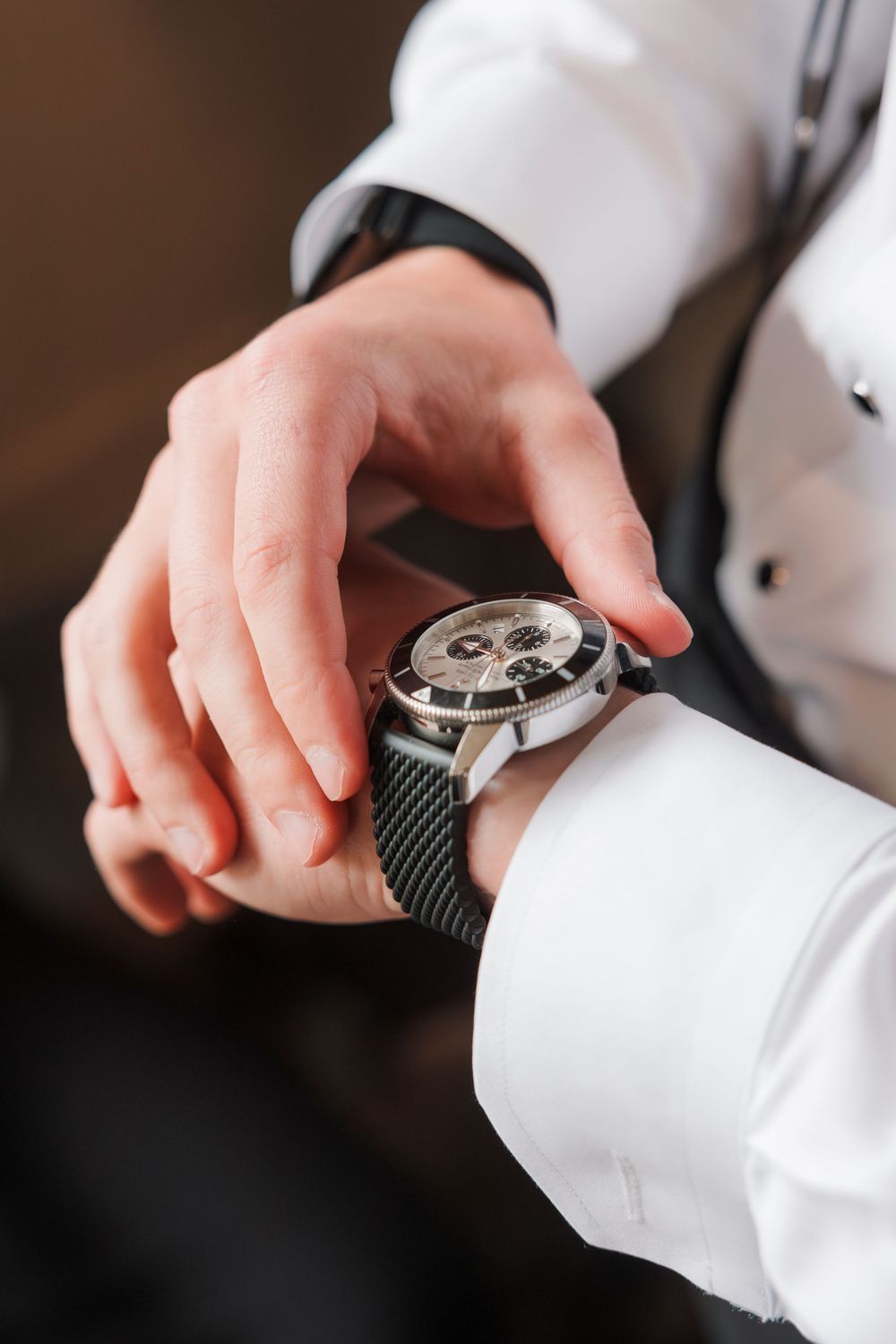 A sequence of close-up shots showing hands adjusting a luxury watch against a dark background.