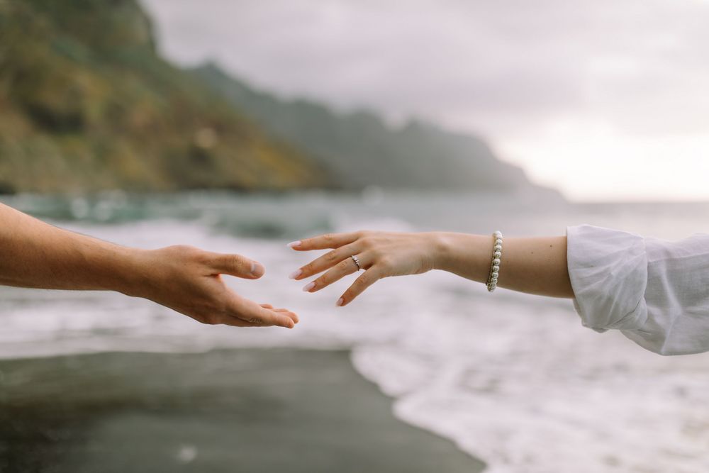 Several hand outreach gestures shot in sequence alongside ocean waves and coastal scenery create a peaceful vignette.