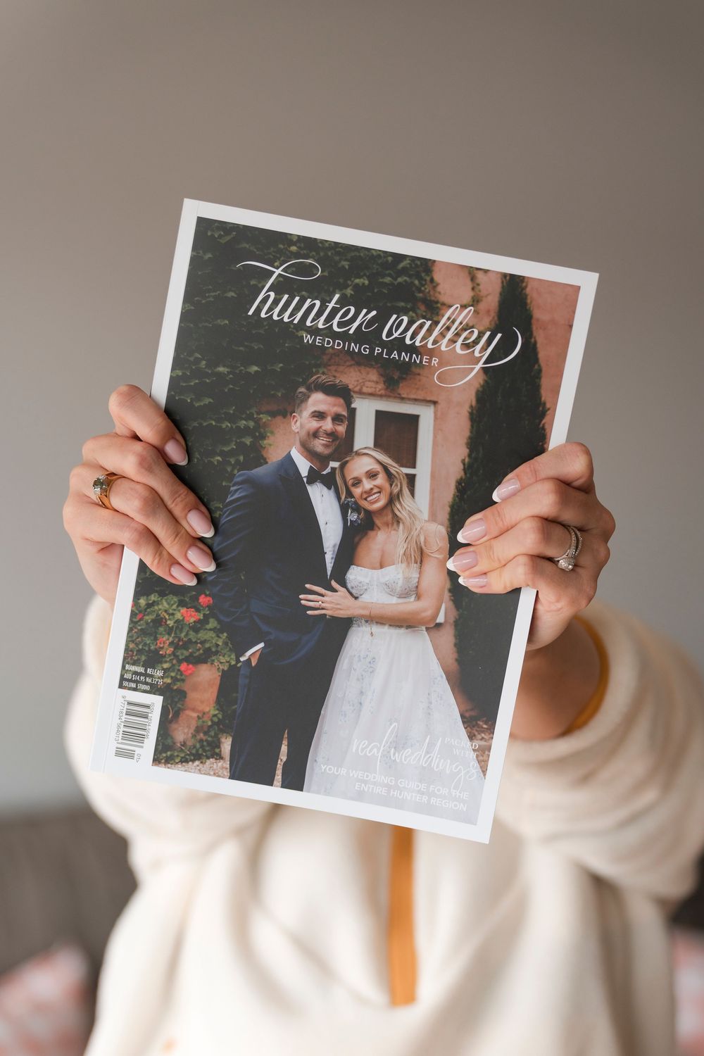 Hands holding a white wedding photo album cover with floral details.