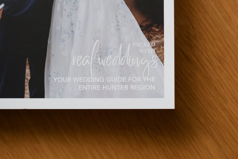 Wedding photography album pages with white designs displayed on a wooden table surface showing elegant bridal details.
