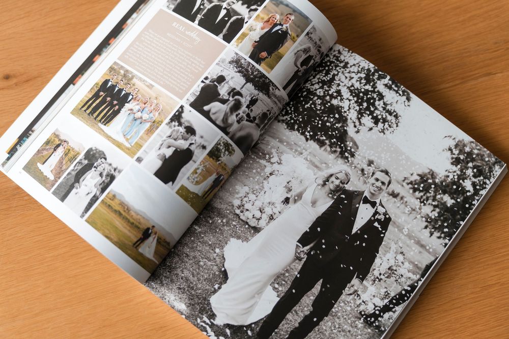 Wedding photo book laid open on wooden surface showing black and white photography spreads.